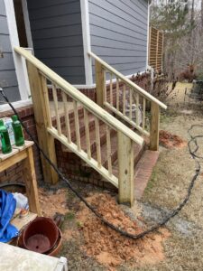 Newly installed wooden handrails and steps leading to a house entrance, a project completed by Lee's Handyman Service LLC in Oxford, MS.