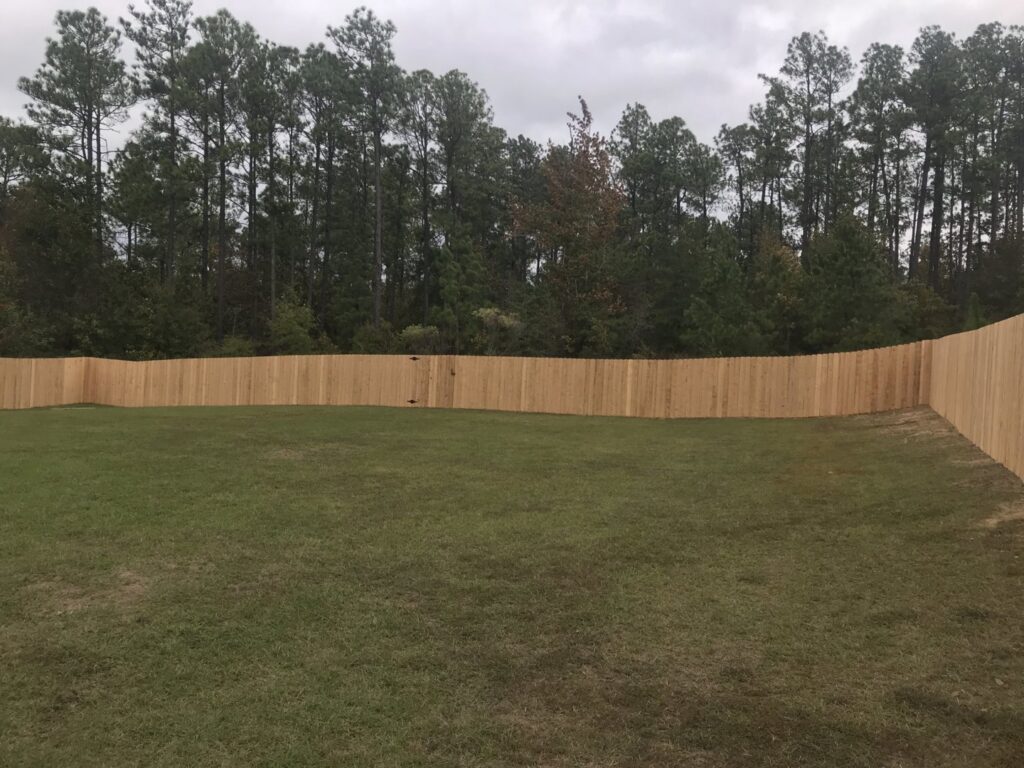 A newly installed wooden privacy fence enclosing a backyard, showcasing fence installation by Steven's Deck and Fence Staining Columbus, GA.