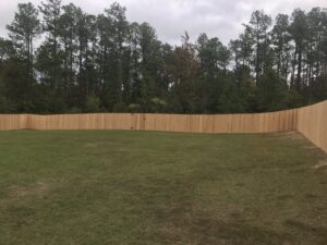 A newly installed wooden privacy fence enclosing a backyard, showcasing fence installation by Steven's Deck and Fence Staining Columbus, GA.