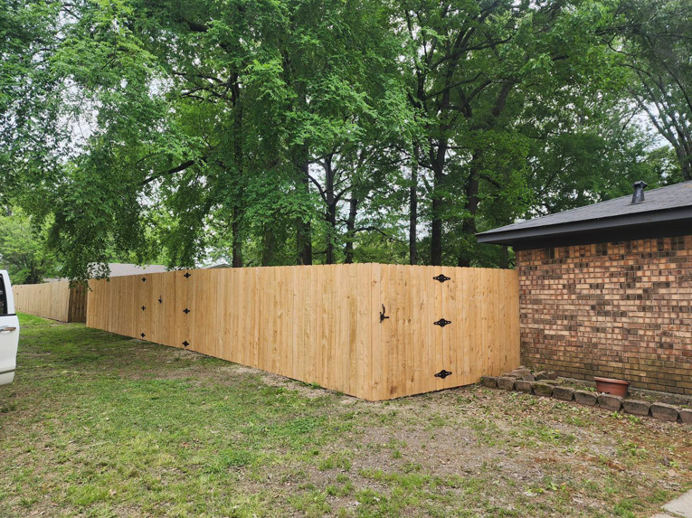 Newly installed wooden privacy fence with black hardware, bordering a yard and house, by Coburns interior and exterior in Services Available In.