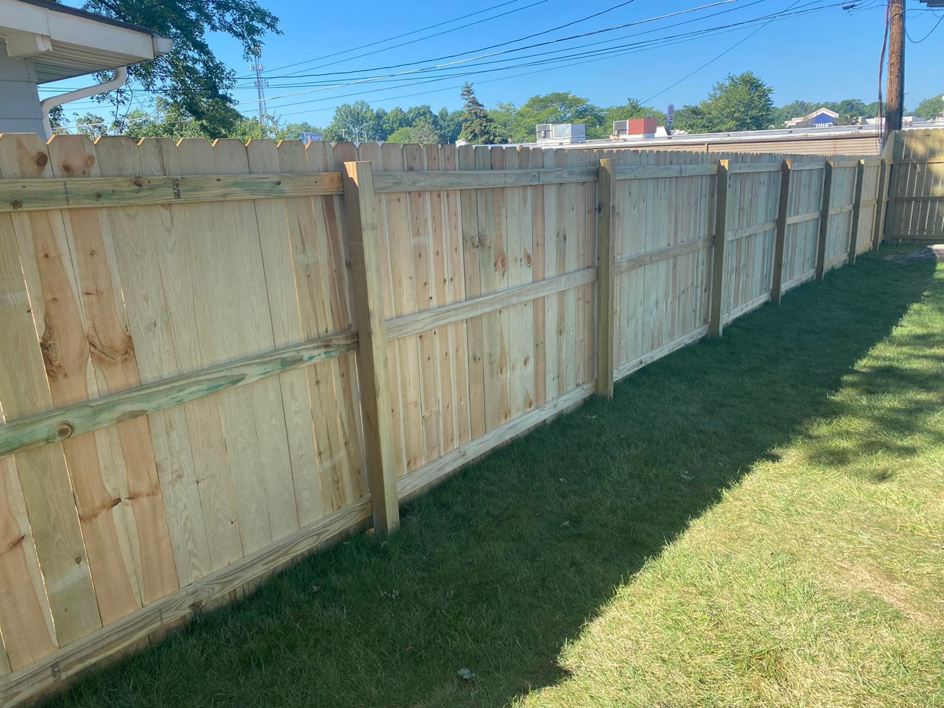 A newly installed wooden privacy fence in a backyard by Lambert's Residential Painting And More LLC in Fort Wayne, IN.