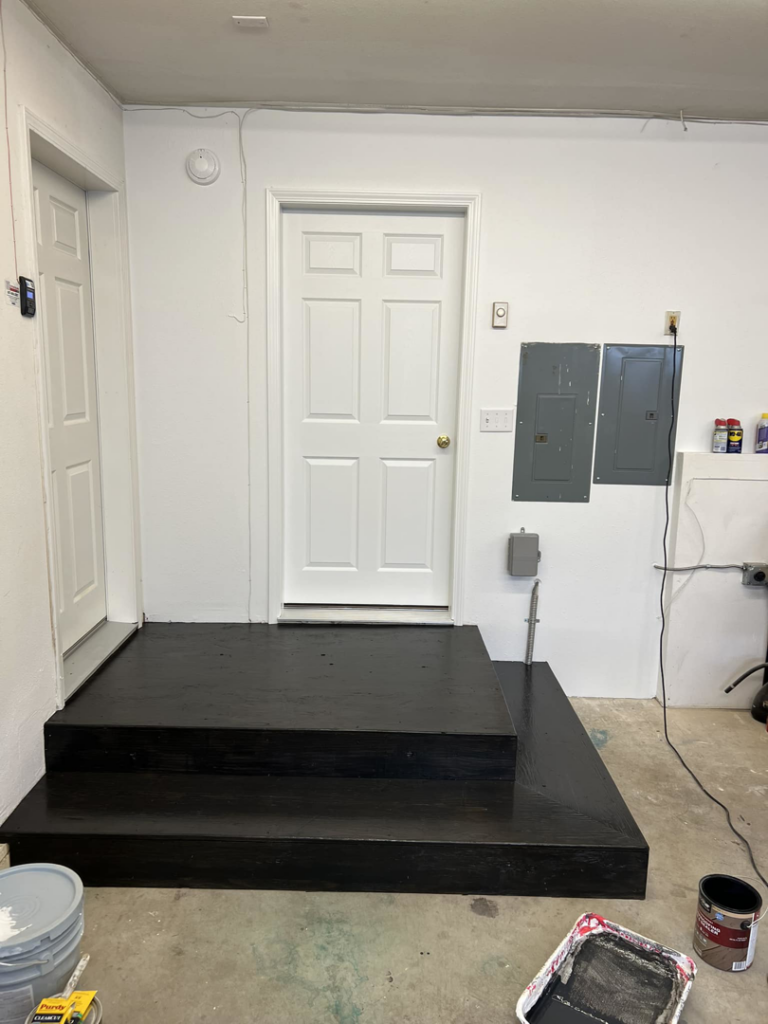 Newly painted black wooden steps and platform in a garage by JKM Services in Solon, OH.
