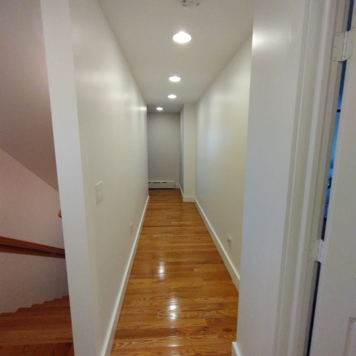 A newly painted white hallway with recessed lighting and wooden floors by SID Painting in West Hartford, CT.