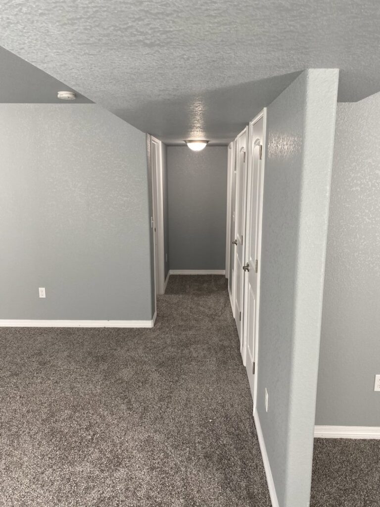 A newly painted room with fresh grey carpet and white trim by Advanced Remodeling Services in Elbert, CO.