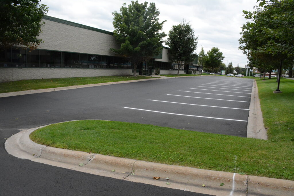A newly paved parking lot with fresh white line markings completed by Buck Blacktop Inc in Little Canada, MN.