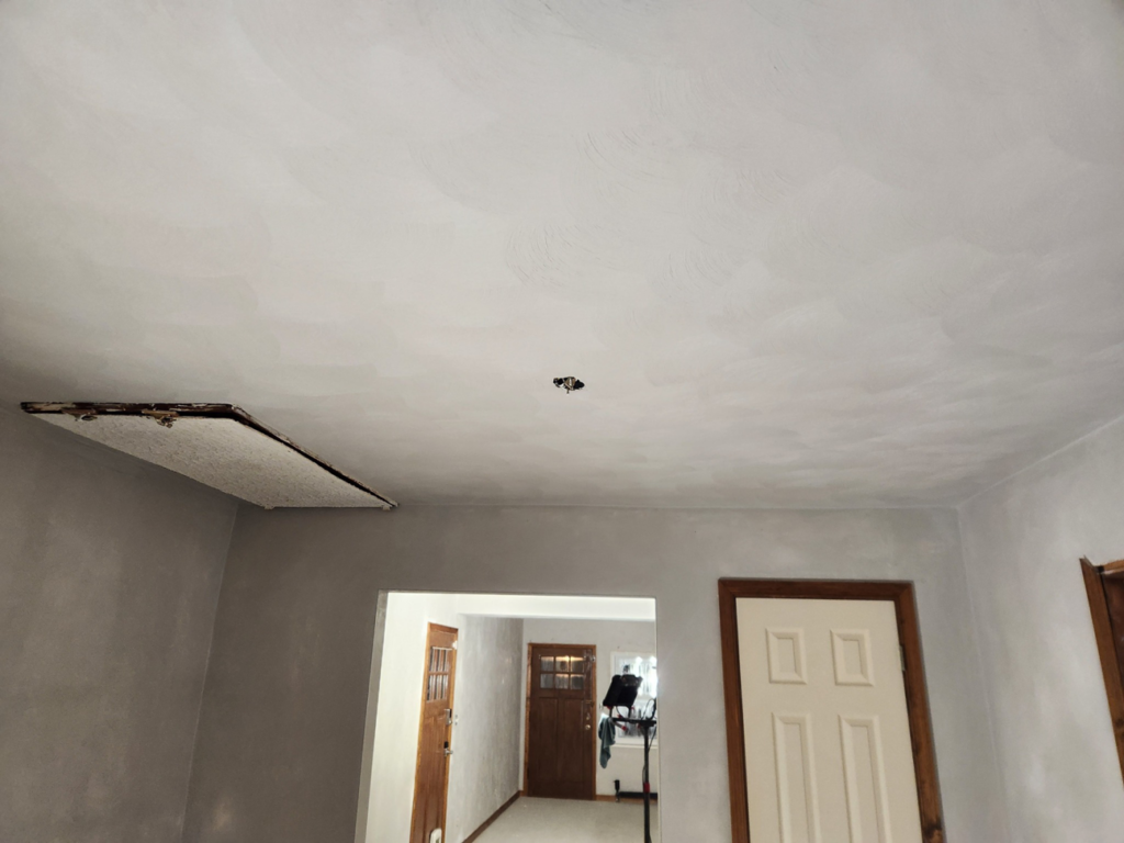A newly plastered ceiling with a repair opening and light fixture prep by Collins Plastering in Deland, FL