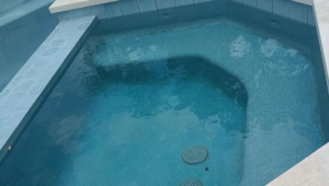 A newly plastered spa, filled with water and featuring blue tiles, completed by Austin Pool Plastering in Austin, TX.