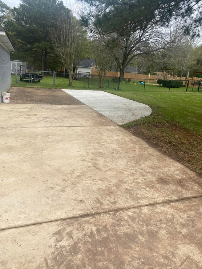 A newly poured concrete patio extension in a backyard by B&H Homes in Shreveport, LA