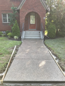 A newly poured concrete sidewalk with forms leading to a brick house by Paris Brothers & Company, Inc in Erie, PA