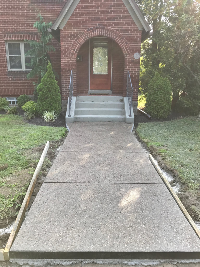 A newly poured concrete sidewalk with forms leading to a brick house by Paris Brothers & Company, Inc in Erie, PA