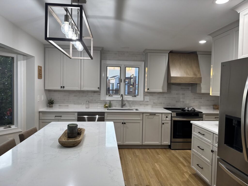 A newly refaced kitchen featuring light gray cabinets, white subway tile backsplash, and a large island by Cincinnati Cabinet Refacing in Cincinnati, OH.