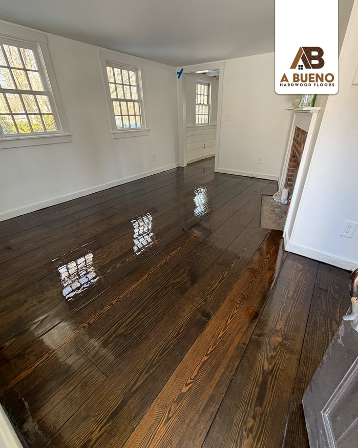 A room with newly refinished dark hardwood floors by Bueno Hardwood Floors in Fairfield, CT