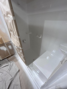 A newly refinished white shower stall with a built-in bench by Immaculate Refinishing in Arlington, TX.