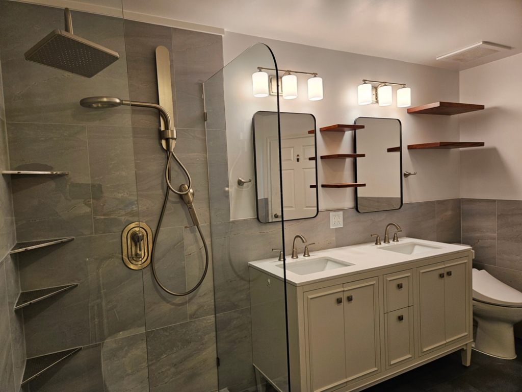 A newly remodeled bathroom showcasing a modern shower with glass enclosure and a double vanity by Huynh Design & Remodeling in Alexandria, VA.