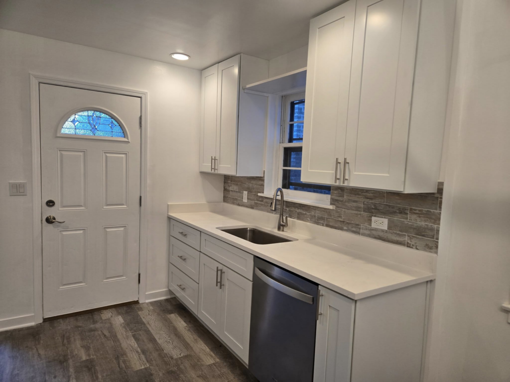 A newly remodeled kitchen with white shaker cabinets, quartz countertops, and a new sink by Specialized Building Services Inc. in Chicago, IL.