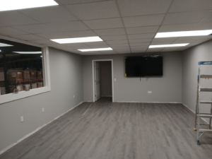A newly remodeled room featuring a wall-mounted TV, new flooring, and fresh paint by Quiros Remodeling in Greenville, SC.