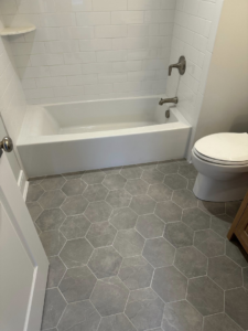 A newly renovated bathroom featuring white subway tile and grey hexagonal floor tiles by Harris Home Creations in Philadelphia, PA.