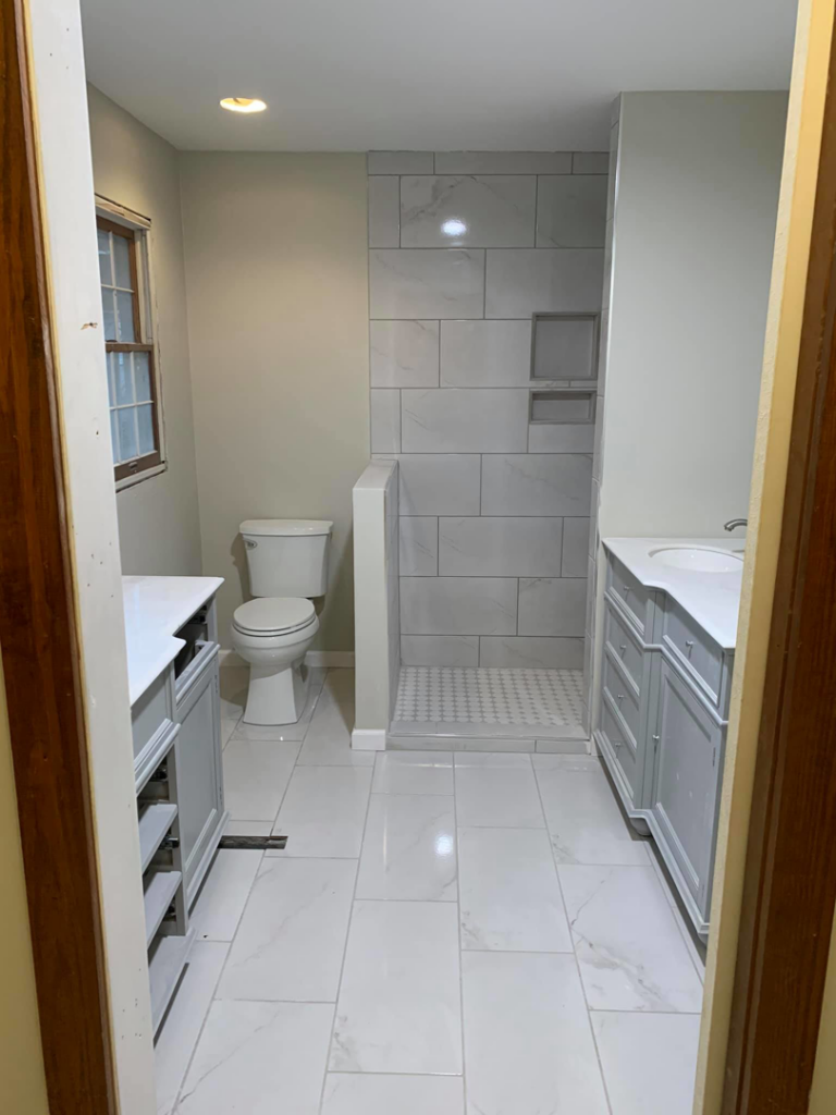 A newly renovated bathroom featuring a walk-in shower, toilet, and double vanity by Ken Sweeney Property Solutions in Knoxville, TN