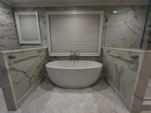 A newly renovated bathroom featuring a freestanding tub and marble-look tiles, completed by Tarr's Home Improvements in Franklin Square, NY.