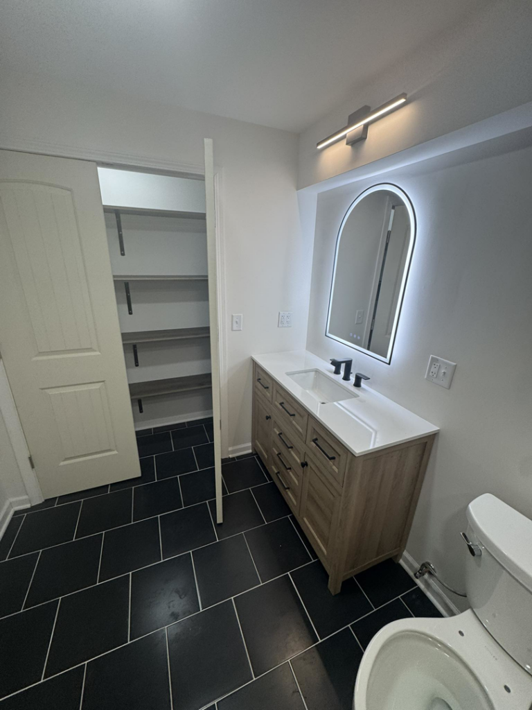 A newly renovated bathroom featuring a modern vanity and mirror installed by Home Improvements by Duane in Racine, WI.