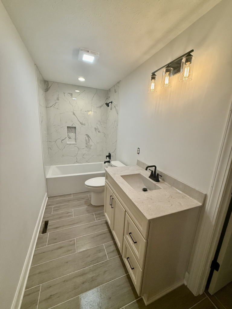 A newly renovated bathroom featuring a modern vanity, toilet, and tiled shower, completed by Phillips Homes, LLC in Elizabethtown, KY.