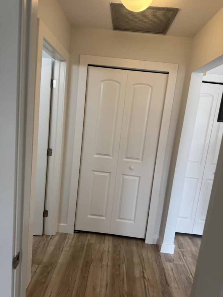 A newly renovated hallway with light wood-look flooring and white bi-fold closet doors by Bradford Brothers Builders Inc. in Cape Coral, FL