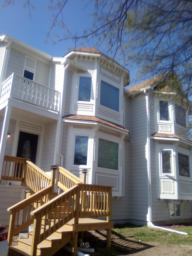 A newly renovated house exterior with new wooden stairs and railings by Picasso Handyman Painters in Wichita, KS.