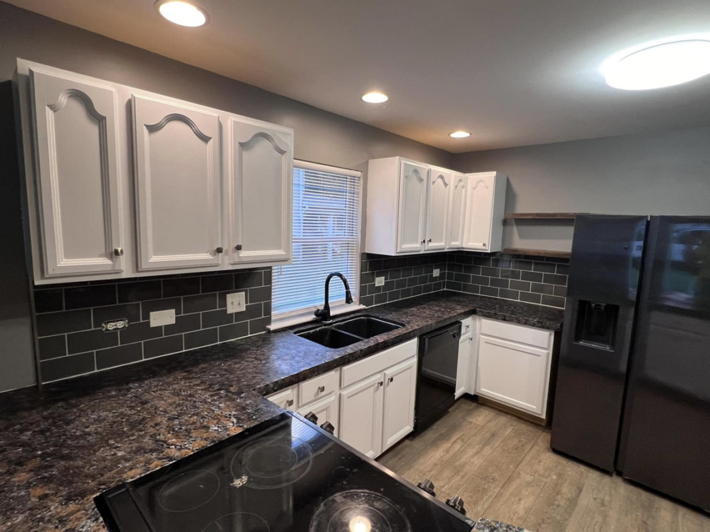 A newly renovated kitchen featuring dark subway tile backsplash, new countertops, and freshly painted cabinets by The Handy Man of Evansville in Evansville, IN.