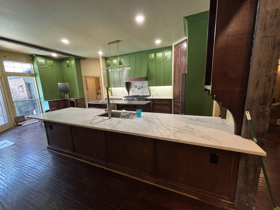 Newly renovated kitchen with green cabinets, large island, and dark wood floors by New Era Painting & Construction, Jefferson, NC.