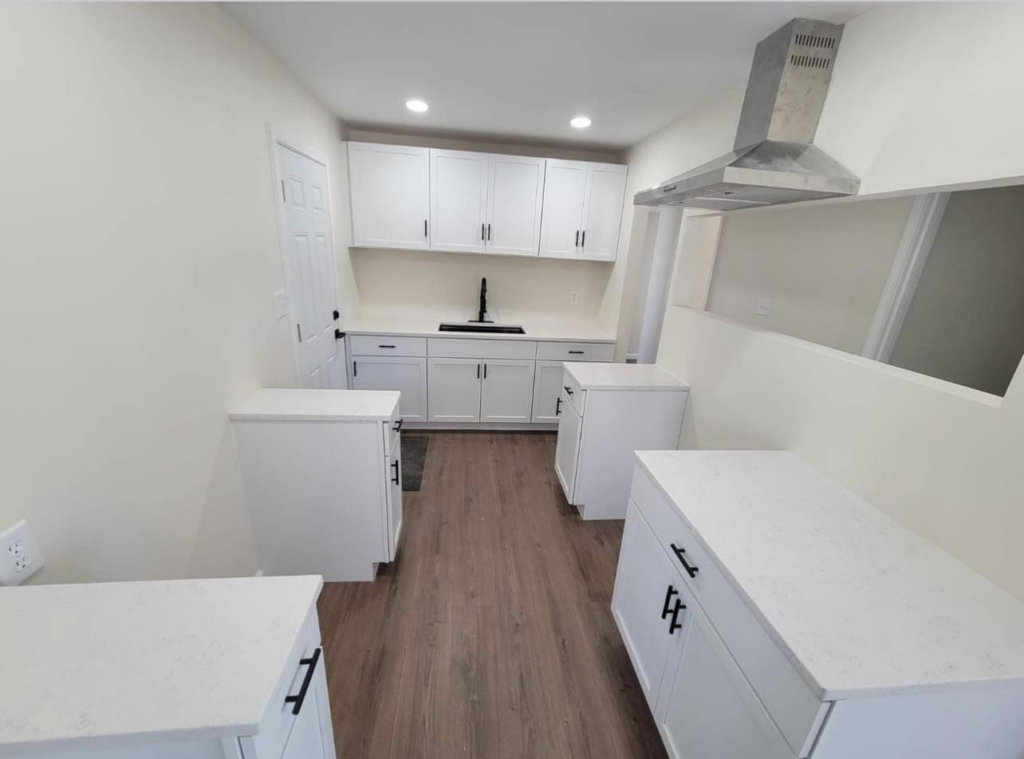 A newly renovated kitchen featuring white cabinets, new flooring, and a modern range hood by J&A Contractor LLC in Milwaukee, WI.