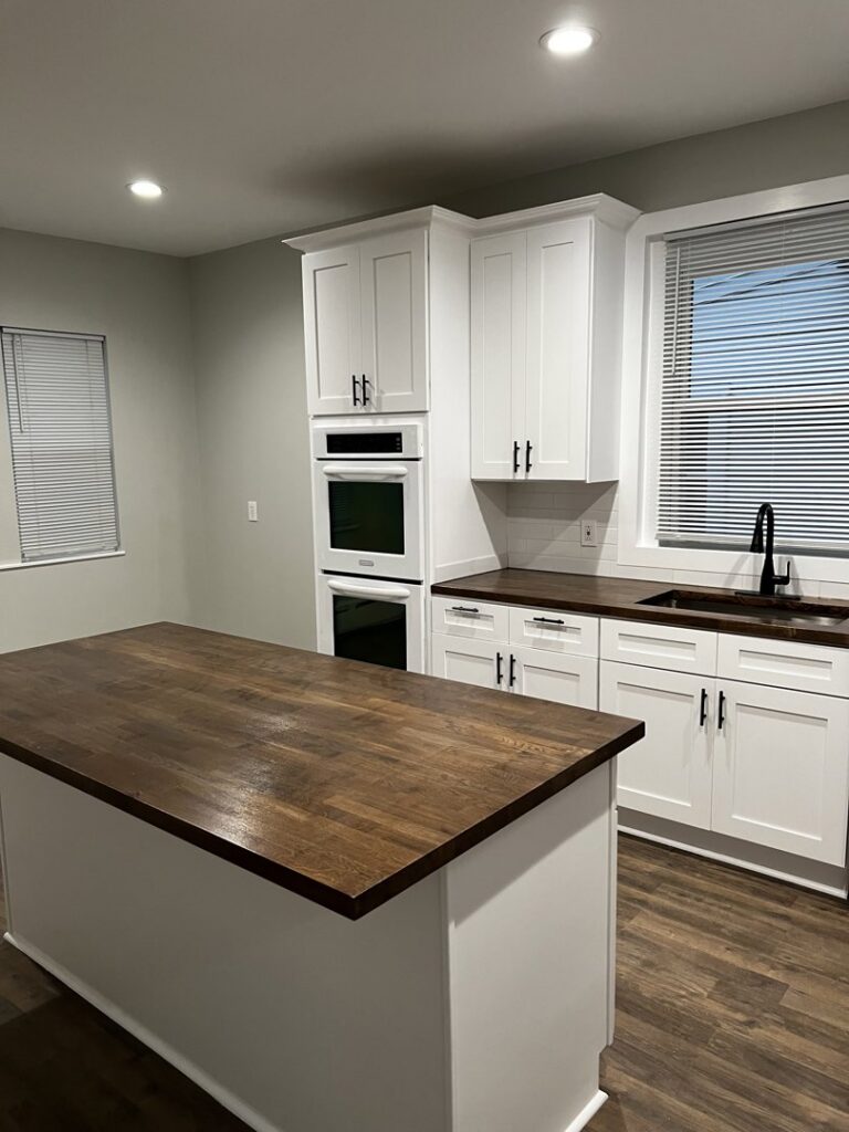 A newly renovated kitchen with white cabinets and dark wood countertops completed by Pro DK Contractor LLC in Chicago, IL.
