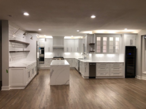 A newly renovated kitchen with white cabinets, a large island, and hardwood floors by Renewing the Home Services in Kansas City, MO.