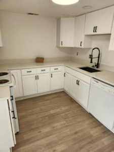 A newly renovated kitchen featuring white cabinets, new countertops, and a black sink by WHE Construction in Virginia Beach, VA