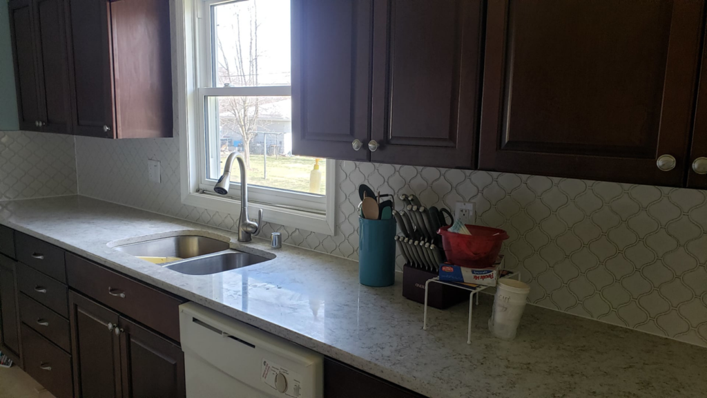 A newly renovated kitchen featuring dark cabinets, light countertops, and a patterned backsplash by Ironside Home Improvements, LLC in Madison, WI.