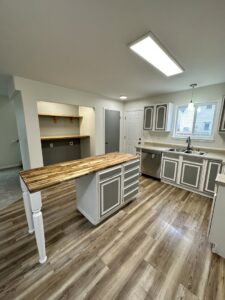 A newly renovated kitchen featuring grey cabinets, wood-look flooring, and a copper sink by Alaskan Residential Rescue in Anchorage, AK.