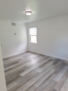 A newly renovated room with modern gray flooring and white walls by Achieve Renovations in Pittsburgh, PA.