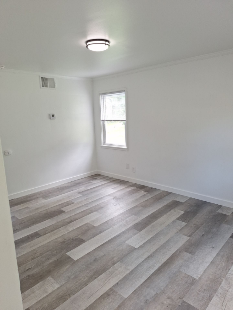 A newly renovated room with modern gray flooring and white walls by Achieve Renovations in Pittsburgh, PA.
