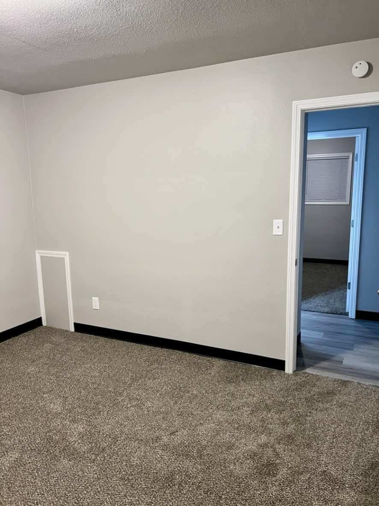 A newly renovated room with fresh paint and new carpet, showcasing handyman work by Get It Done in Sioux Falls, SD.