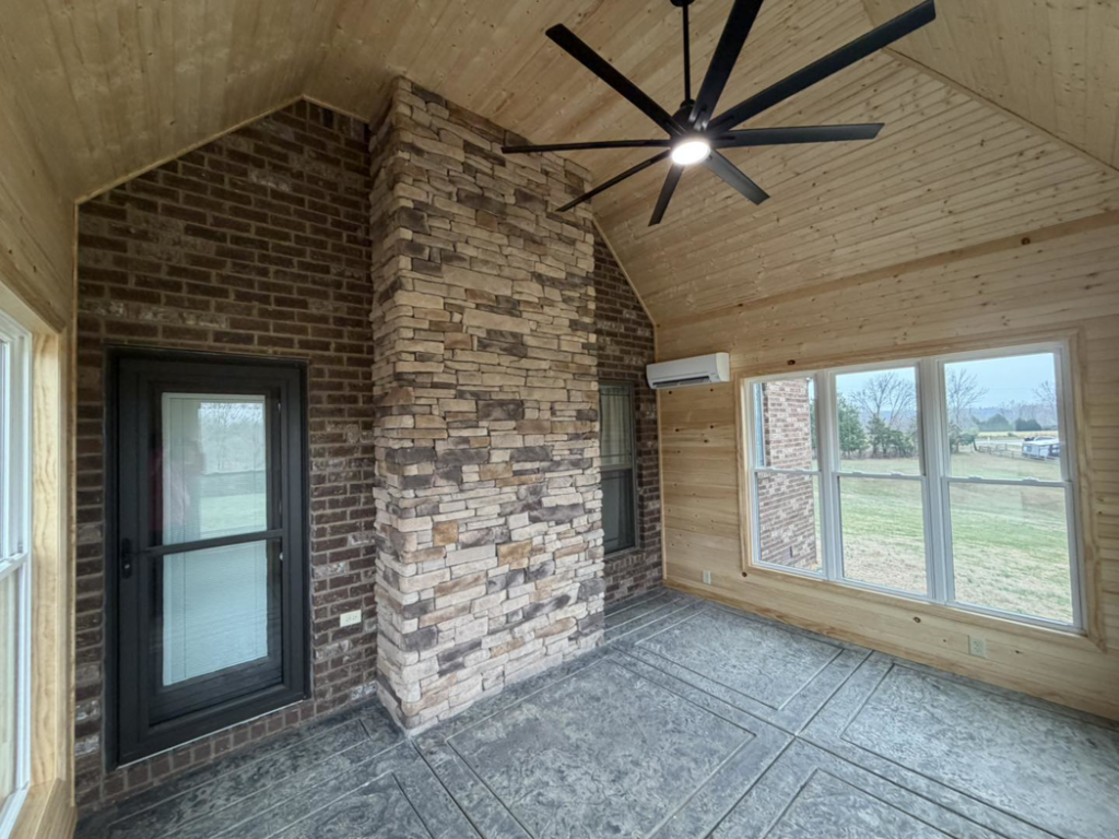 A newly renovated room featuring a ceiling fan, stone fireplace, and mini-split AC installed by JM Home and Property Services in Clarksville, TN