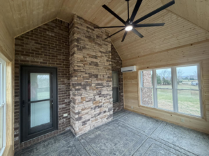 A newly renovated room featuring a ceiling fan, stone fireplace, and mini-split AC installed by JM Home and Property Services in Clarksville, TN