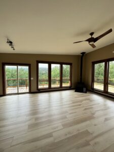A newly renovated room featuring new flooring, a ceiling fan, and a wood stove by Alaskan Residential Rescue in Anchorage, AK.