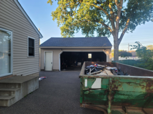 A newly roofed garage with a construction debris dumpster nearby, completed by INT-X Remodeling LLC in Woodbury, MN.