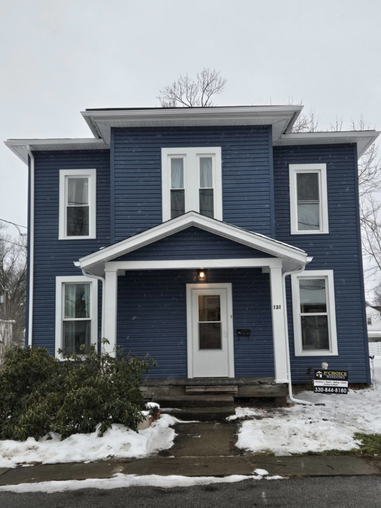A newly sided blue house with new white windows, a completed project by 1st Choice Windows in Canton, OH.
