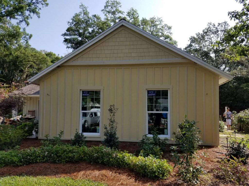 A newly sided house exterior with fresh yellow siding and new windows completed by Alejandro Melo Contractor corp in Tampa, FL.