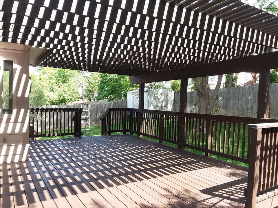 A newly stained wooden deck with a pergola, a completed project by Brauny Home Services, LLC in Arvada, CO