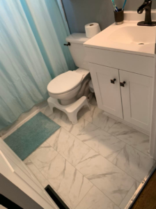 A newly installed tiled bathroom floor with a white toilet and vanity by Humphrey's Helping Hands in Clarksville, TN.