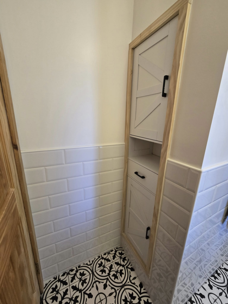 A newly tiled bathroom wall featuring a custom built-in cabinet by All In Remodeling Services LLC in Arvada, CO.