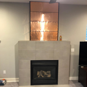 A newly tiled fireplace with custom copper paneling installed by Smitty Construction Services LLC in Bend, OR.