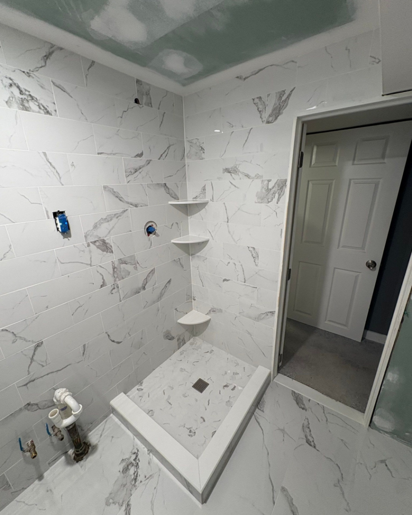 A newly tiled shower area with corner shelves and a shower pan installed by Clearview Home Remodeling in Parkville, MD.