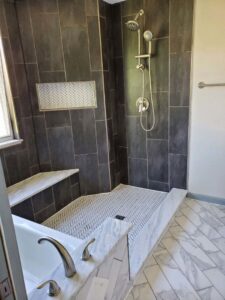 A newly tiled shower with a built-in bench and modern fixtures, completed by Infinite Creations Construction, LLC in Denver, CO